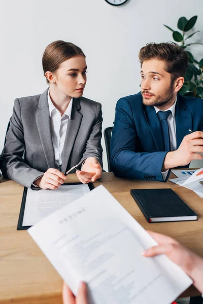 Selective focus of recruiters looking at each other near employee holding resume in office — Stock Photo