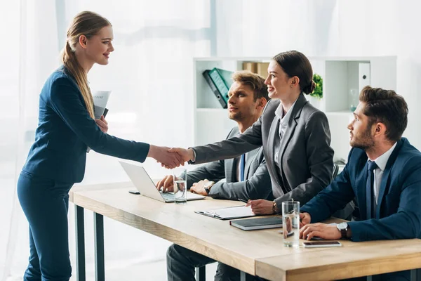 Funcionário sorridente apertando as mãos com recrutador no escritório — Fotografia de Stock