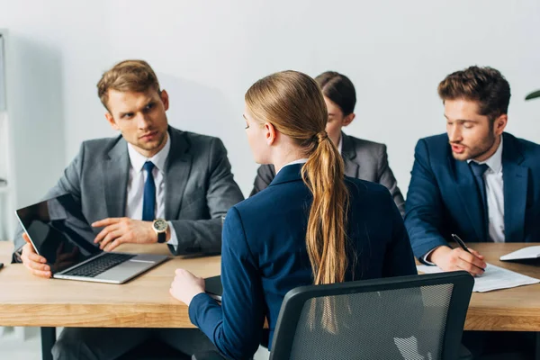 Enfoque selectivo del empleado mirando el ordenador portátil durante la entrevista de trabajo con los reclutadores en la oficina - foto de stock