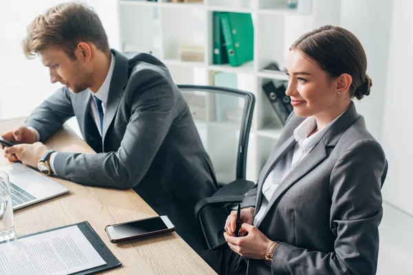 Selektiver Fokus eines lächelnden Personalvermittlers, der neben seinem Amtskollegen am Tisch sitzt — Stockfoto