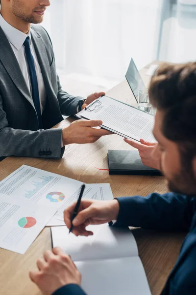 Selektiver Fokus des Mitarbeiters mit Lebenslauf in der Nähe des Recruiters, der am Tisch am Notizbuch schreibt — Stockfoto