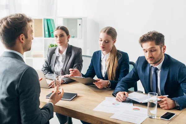 Recruteurs à la recherche de documents lors d'un entretien d'embauche avec un employé au bureau — Photo de stock