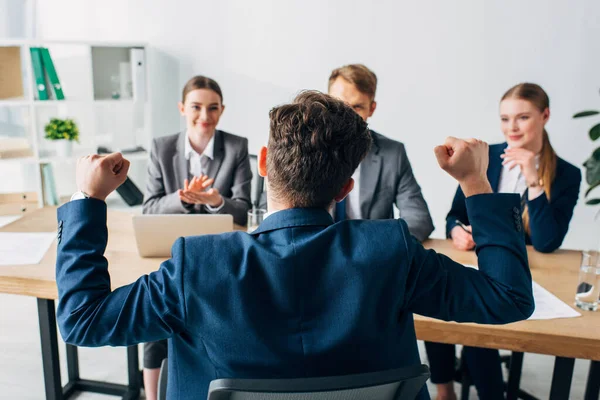 Selective focus of employee showing yes gesture near smiling recruiters in office — Stock Photo