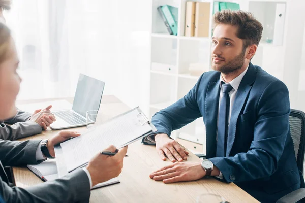 Selective focus of employee looking at recruiter with resume during job interview — Stock Photo