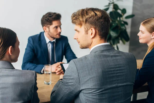 Foco seletivo dos recrutadores olhando uns para os outros durante a entrevista de emprego com o funcionário — Fotografia de Stock