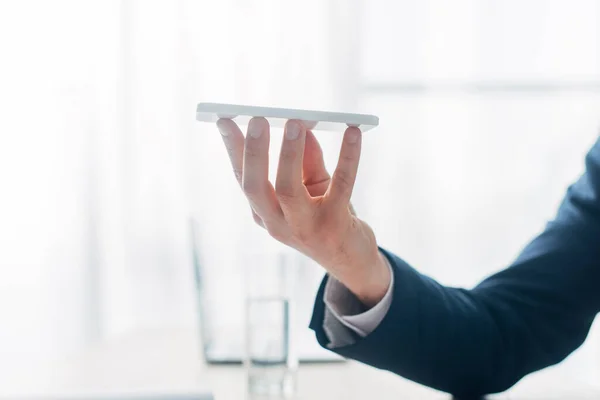 Ausgeschnittene Ansicht eines Mannes, der sein Smartphone am Tisch hält — Stockfoto