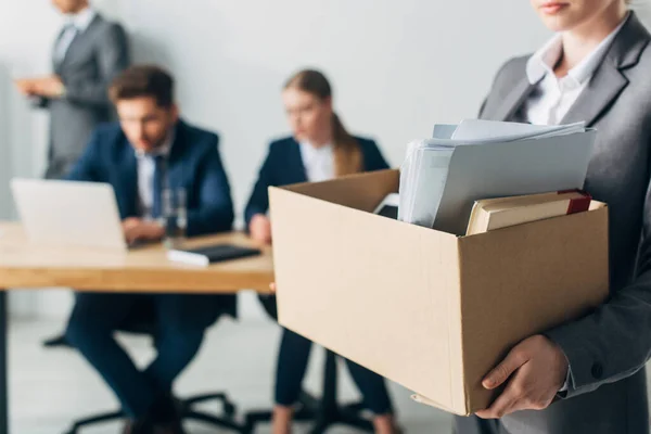 Focus selettivo della donna licenziata in possesso di scatola di cartone con libro e carte in ufficio — Foto stock