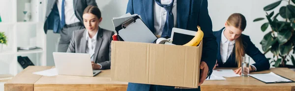 Panoramic shot of dismissed man holding box with papers and digital tablet in office — Stock Photo