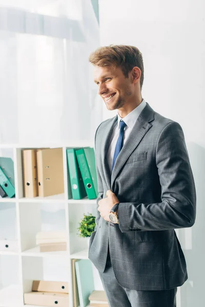 Hombre de negocios guapo en traje sonriendo en la oficina - foto de stock