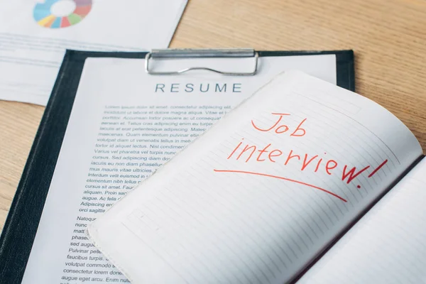 Cuaderno abierto con letras de entrevista de trabajo cerca de curriculum vitae y documentos sobre la mesa — Stock Photo