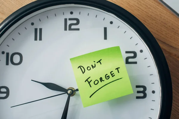 Top view of sticky note with dont forget lettering on clock on table — Stock Photo