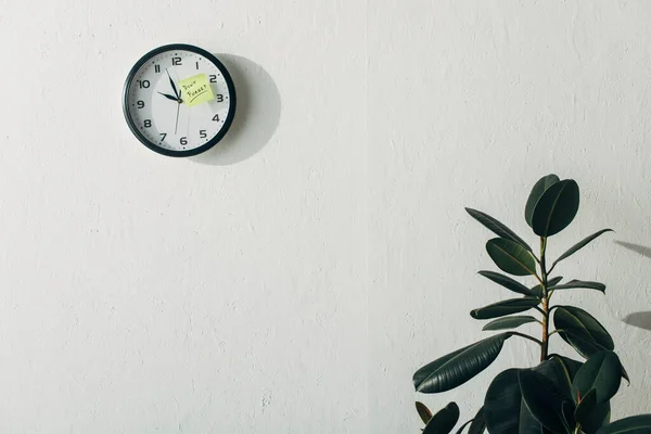 Nota appiccicosa con scritte da non dimenticare sull'orologio vicino alla pianta in ufficio — Foto stock