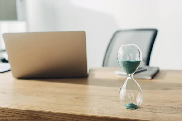 Вибірковий фокус пісочного годинника на столі біля ноутбука в офісі — стокове фото