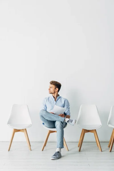 Schöner Angestellter schaut weg und hält Lebenslauf auf Stuhl im Büro — Stockfoto
