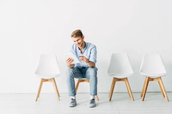 Усміхнений працівник вказує пальцем на цифровий планшет на стілець в офісі — стокове фото