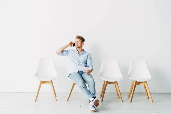 Smiling man talking on smartphone and holding resume in office — Stock Photo