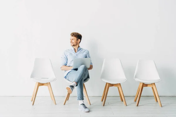 Belle employée souriant et utilisant un ordinateur portable au bureau — Photo de stock