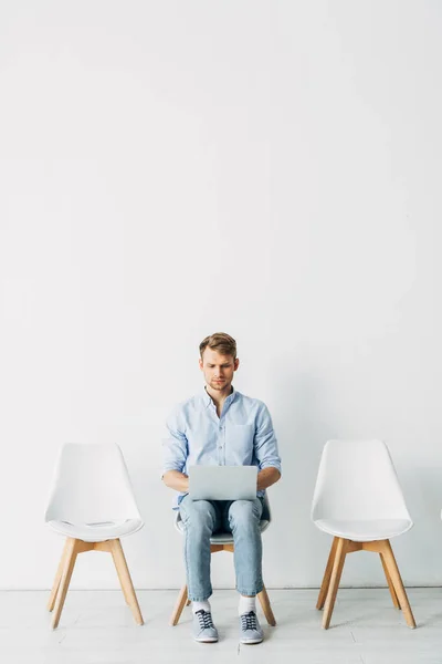 Beau employé utilisant un ordinateur portable en attendant l'entrevue d'emploi au bureau — Photo de stock