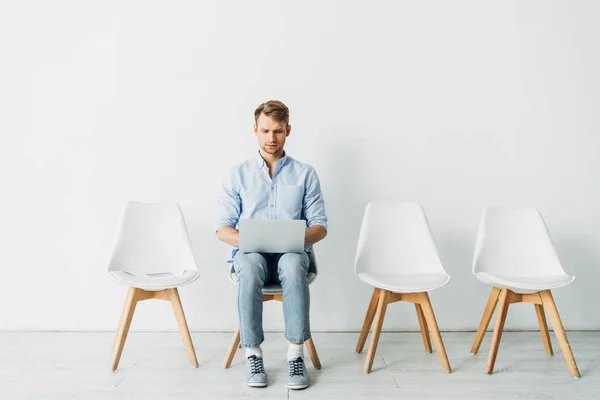 Schöne Angestellte mit Laptop in der Nähe Lebenslauf und Smartphone auf Stuhl im Büro — Stockfoto
