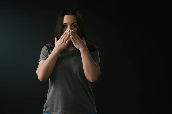 Front view of plus size girl covering mouth with hands on black background — Stock Photo