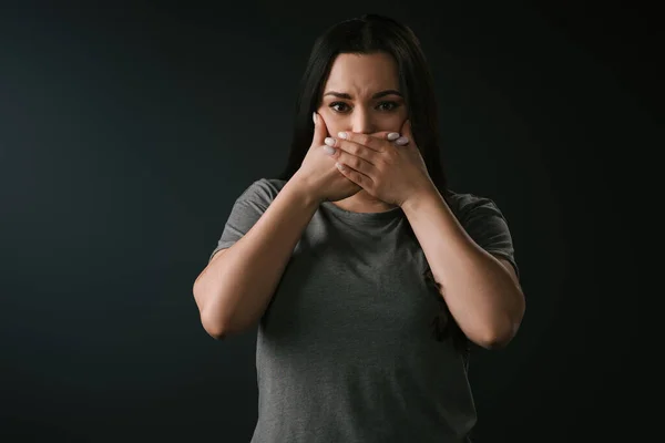 Vista frontal da menina bonita plus size gesticulando silêncio, cobrindo a boca com as mãos no fundo preto — Fotografia de Stock