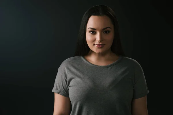 Front view of attractive smiling plus size girl on black background — Stock Photo