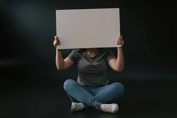 Vorderseite des Plus-Size-Mädchens mit leerem Brett auf schwarzem Hintergrund — Stockfoto