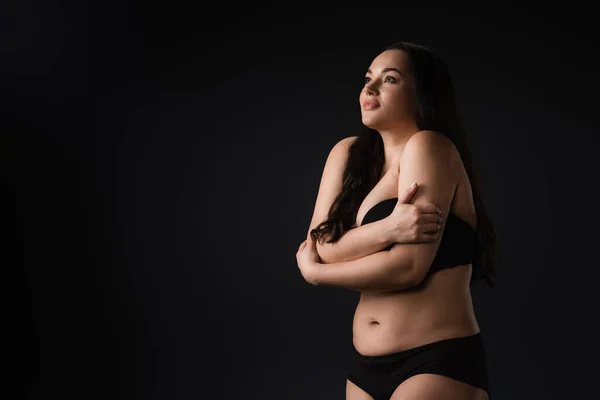 Ispirato grazioso plus size ragazza abbracciandosi isolato su nero — Foto stock