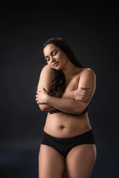 Vista frontale di plus size ragazza godendo e abbracciando il suo corpo su sfondo nero — Foto stock