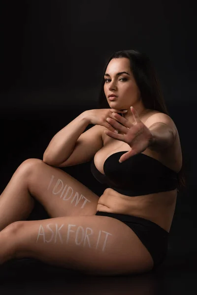 Plus size model in underwear with stop gesture and lettering I Did not Ask For It on body on black background — Stock Photo