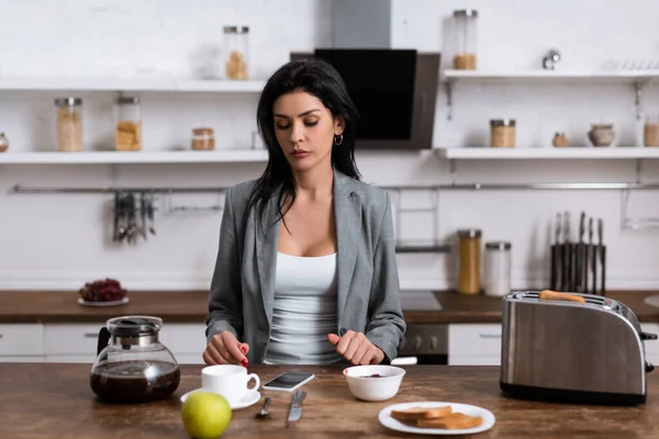 Traurige Geschäftsfrau blickt beim Frühstück auf Smartphone mit leerem Bildschirm, Konzept für häusliche Gewalt — Stockfoto