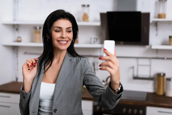 Selective focus of smiling businesswoman with black dot on palm taking selfie, domestic violence concept — Stock Photo