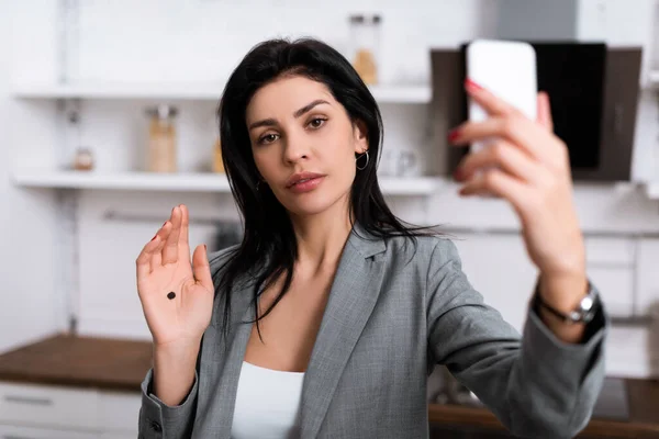 Selective focus of attractive businesswoman with black dot on palm taking selfie, domestic violence concept — Stock Photo