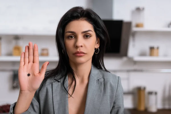 Sad businesswoman showing hand with black dot on palm, domestic violence concept — Stock Photo