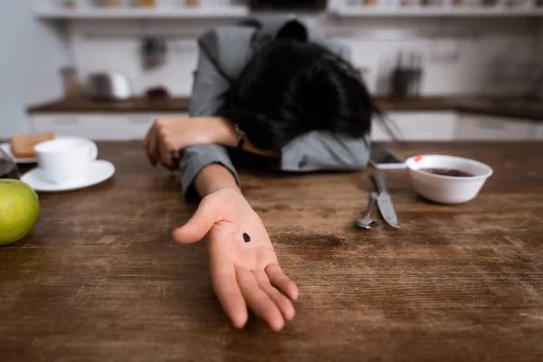 Selective focus of businesswoman showing hand with black dot on palm while covering face, domestic violence concept — Stock Photo