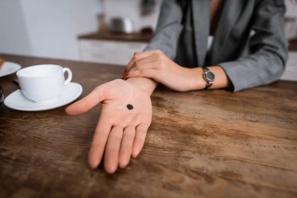 Cropped view of woman showing hand with black dot on palm near cup, domestic violence concept — Stock Photo