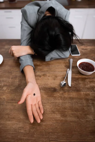 Businesswoman showing hand with black dot on palm while covering face, domestic violence concept — Stock Photo