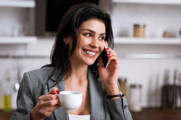 Femme d'affaires heureuse tenant une tasse de café et parlant sur smartphone tout en cachant le problème de la violence domestique — Photo de stock