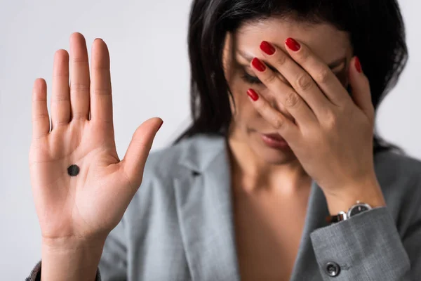 Enfoque selectivo de la mujer de negocios triste mostrando la mano con el punto negro en la palma de la mano y cubriendo los ojos aislados en blanco, concepto de violencia doméstica - foto de stock