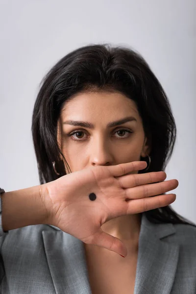 Empresária com ponto preto na palma cobrindo boca isolada no branco, conceito de violência doméstica — Fotografia de Stock