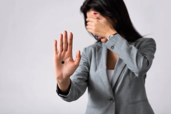 Selective focus of businesswoman with black dot on palm covering face isolated on white, domestic violence concept — Stock Photo