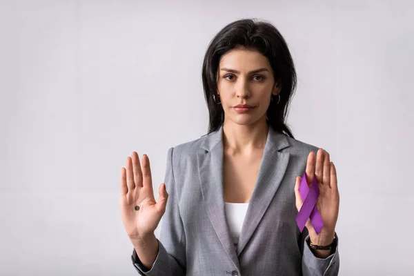 Mujer de negocios con el punto negro en la palma de la mano que sostiene la cinta púrpura en blanco, concepto de violencia doméstica - foto de stock