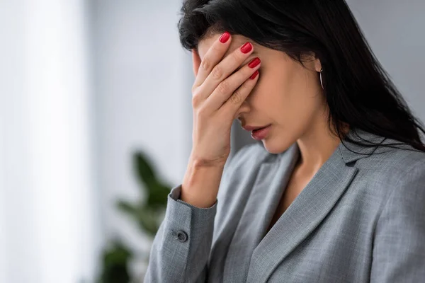 Frustrated businesswoman with bruise on hand covering eyes, domestic violence concept — Stock Photo