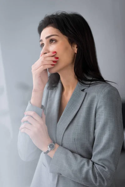 Frustrada empresaria con moretones en la mano cubriendo la boca, concepto de violencia doméstica - foto de stock