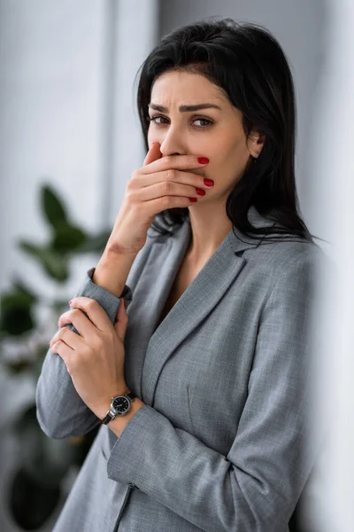 Disgustada mujer de negocios con moretones en la mano cubriendo la boca, concepto de violencia doméstica - foto de stock