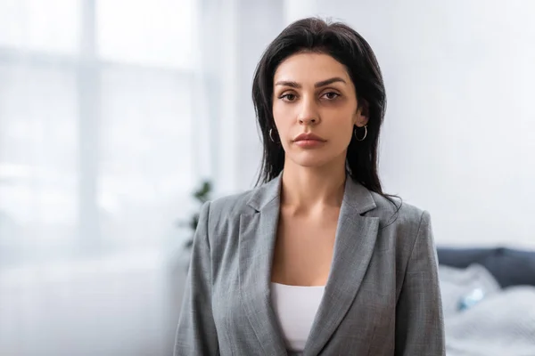 Mujer de negocios molesta con moretones en la cara mirando a la cámara, concepto de violencia doméstica - foto de stock