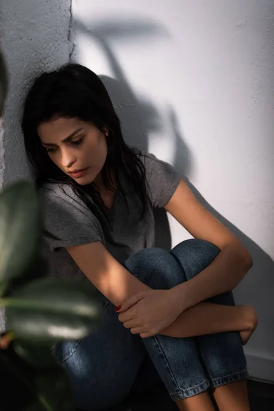 Selective focus of upset woman with bruise on face sitting on floor at home, domestic violence concept — Stock Photo