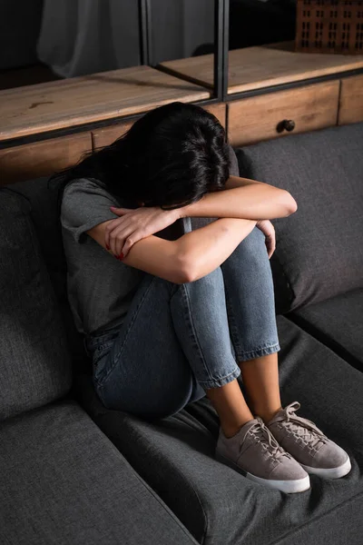 Verärgerte Frau verdeckt Gesicht, während sie auf Sofa sitzt, Konzept für häusliche Gewalt — Stockfoto