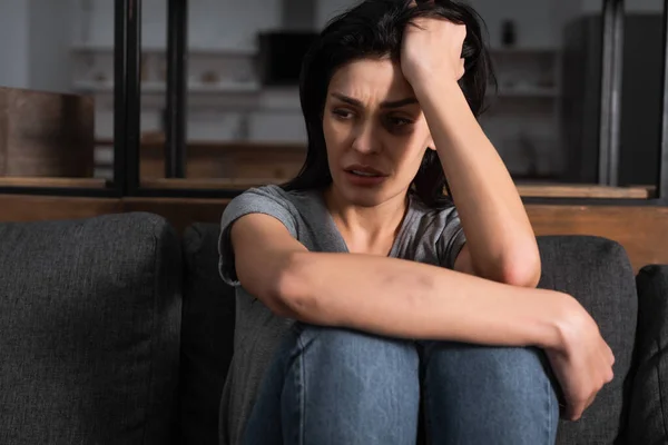 Mujer triste con moretones en la cara sentada en el sofá, concepto de violencia doméstica — Stock Photo