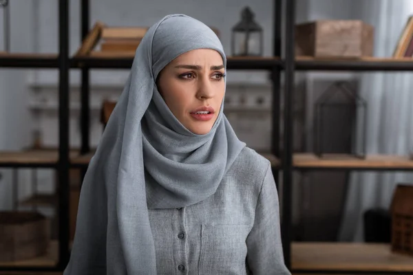 Upset muslim woman in hijab looking away in living room, domestic violence concept — Stock Photo